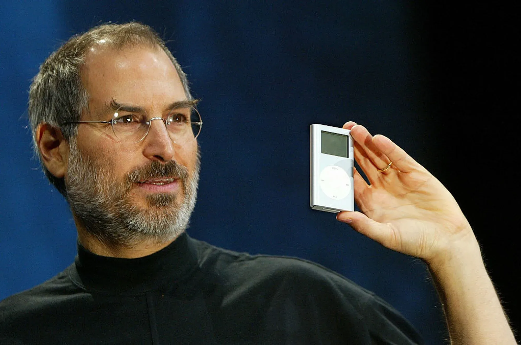 Steve Jobs apresentando o iPod. Com a adoção de RSS pelo iTunes em 2005, o formato simples e aberto foi combustível para o ecossistema de podcasts que ajudou a transformar o iPod num fenômeno.