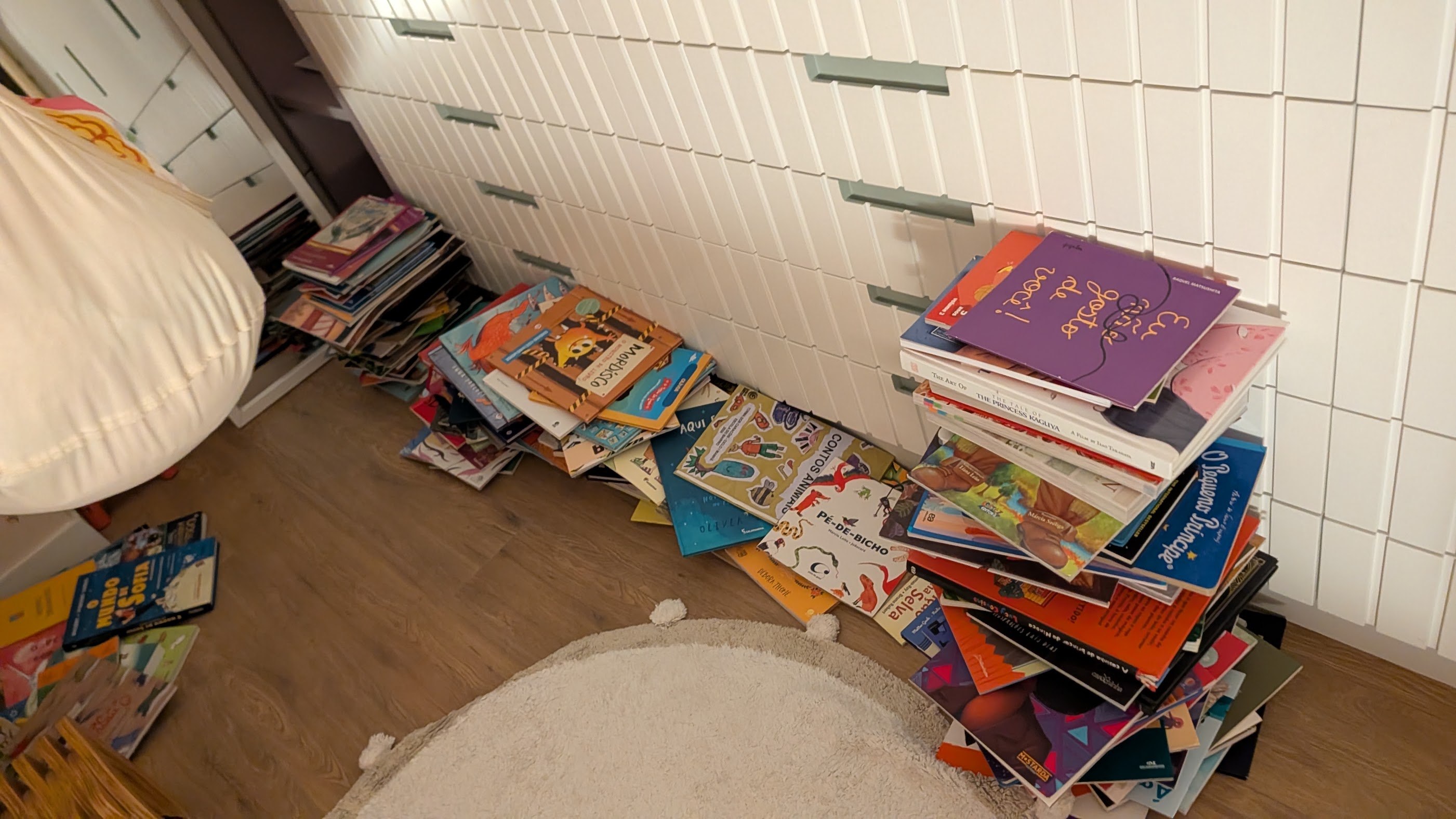 A bagunça da arrumação: pilhas de livros infantis pelo chão do quarto
